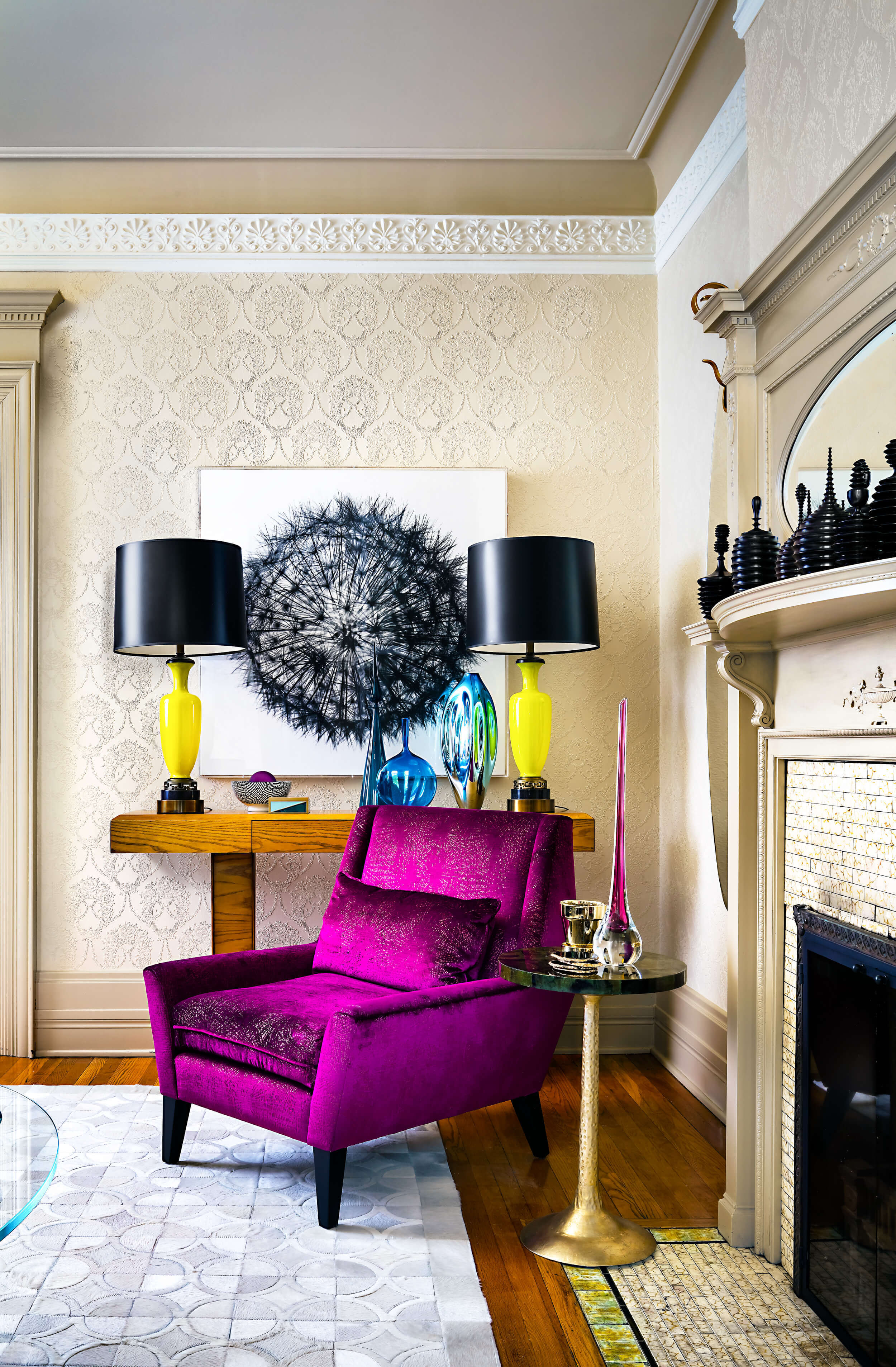 Purple velvet lounge chair, gold accent table, wood console, yellow lamps with black shades, motif wallpaper and decorative moulding Purple velvet lounge chair, gold accent table, wood console, yellow lamps with black shades, motif wallpaper and decorative moulding