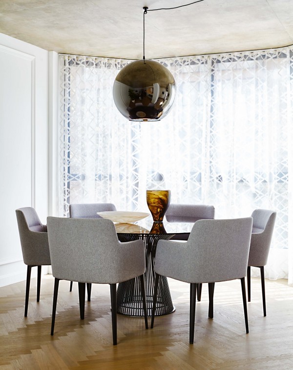 Dining room with herringbone wood floor, concrete ceiling, shiny globe pendant light, white French panel walls, glass table with gray chairs and sheer drapes Dining room with herringbone wood floor, concrete ceiling, shiny globe pendant light, white French panel walls, glass table with gray chairs and sheer drapes