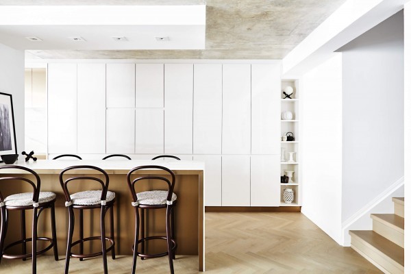 High gloss white kitchen cabinetry, pot lights, waterfall island and wood counter stools, concrete ceiling and herringbone wood floor High gloss white kitchen cabinetry, pot lights, waterfall island and wood counter stools, concrete ceiling and herringbone wood floor