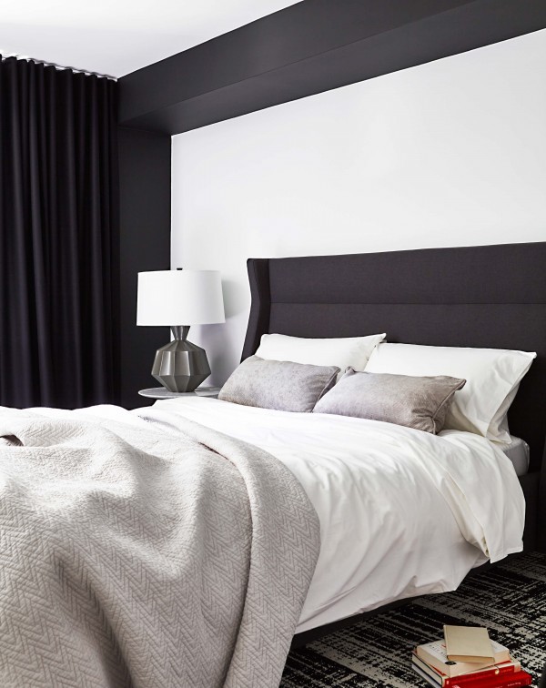 Bedroom with gray bed, gray coverlet, white bedding, tulip end table, grey table lamp, black and white walls and carpet tile, and black floor-to-ceiling curtains Bedroom with gray bed, gray coverlet, white bedding, tulip end table, grey table lamp, black and white walls and carpet tile, and black floor-to-ceiling curtains