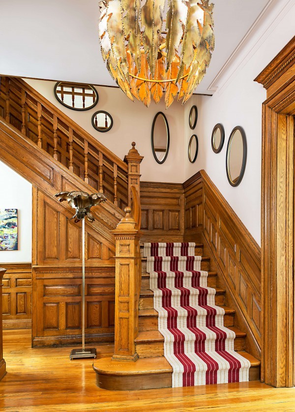 Majestic wood staircase with striped runner, mirror gallery wall, metal leaf chandelier, metal floor lamp, and hardwood floor Majestic wood staircase with striped runner, mirror gallery wall, metal leaf chandelier, metal floor lamp, and hardwood floor