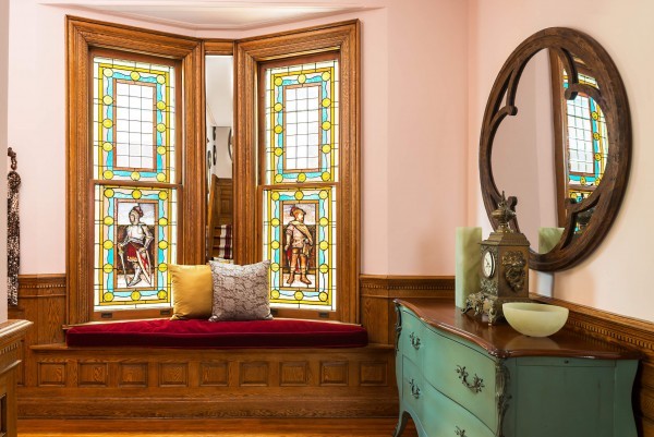 Original stained glass windows with bench, green commode, round mirror, and wood paneling Original stained glass windows with bench, green commode, round mirror, and wood paneling