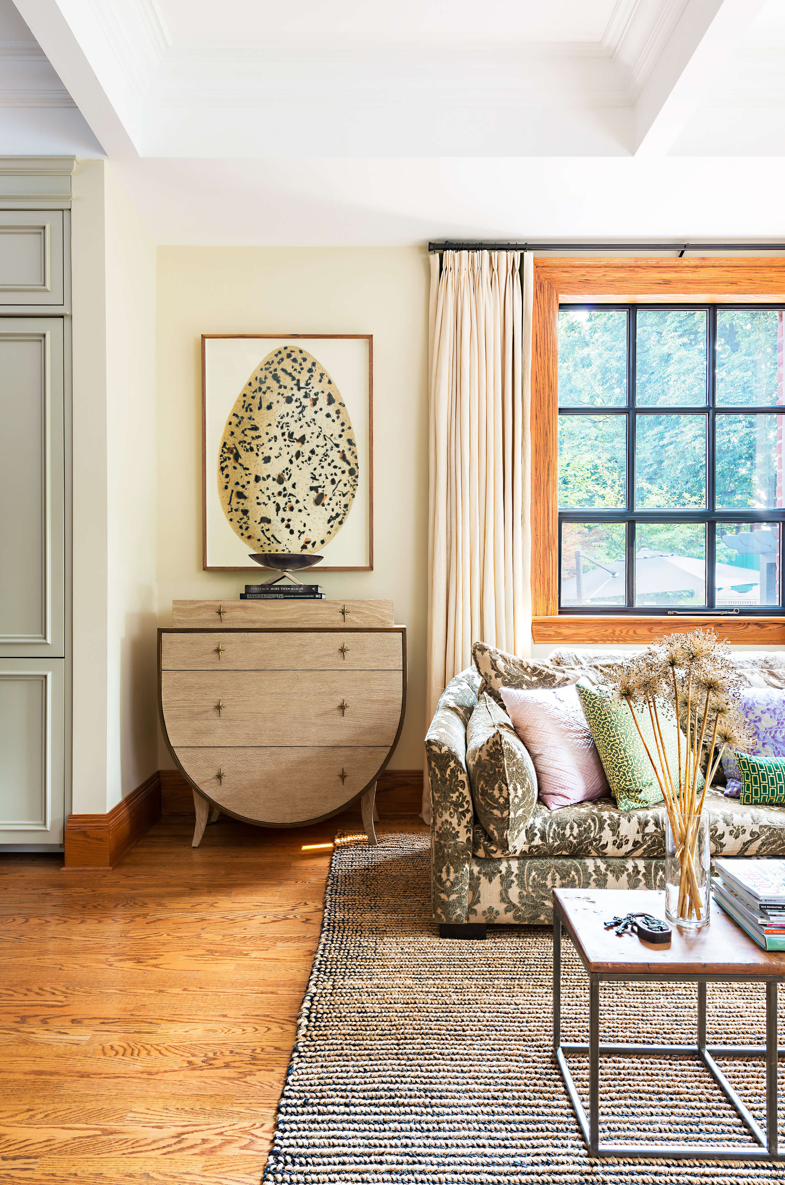 Neutral living space with egg artwork, wood side table, sofa, original hardwood floor and sisal rug Neutral living space with egg artwork, wood side table, sofa, original hardwood floor and sisal rug
