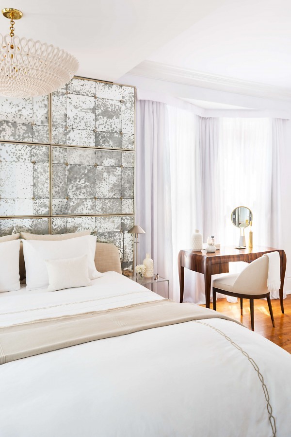 Beige bed with distressed mirror, wood desk, chair, pendant light and floor to ceiling white sheers Beige bed with distressed mirror, wood desk, chair, pendant light and floor to ceiling white sheers