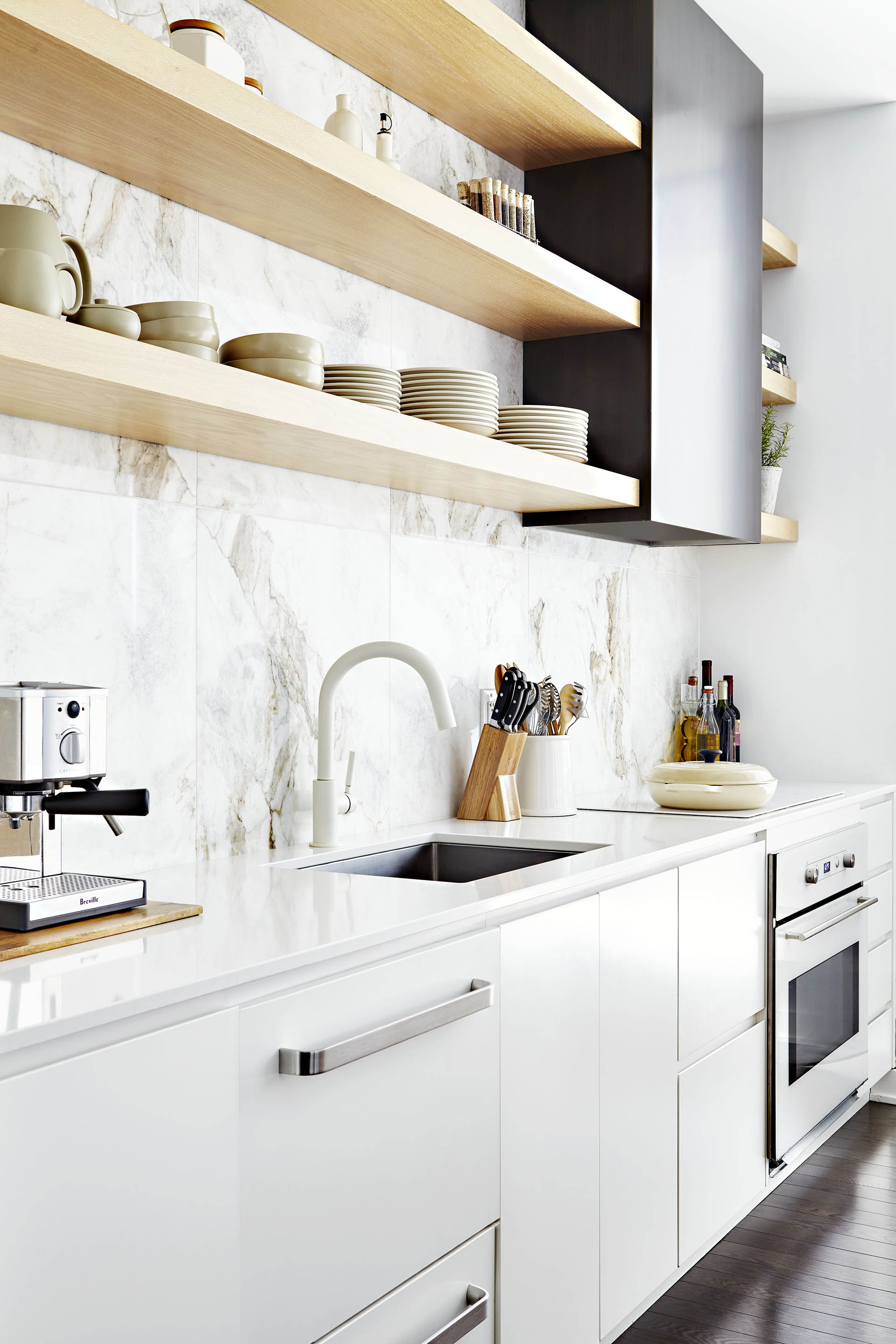White kitchen cabinets, marble large scale blacksplash tile, dark metal hood fan, panel ready appliances, white range, white cooktop, white quartz counter top, limed oak open shelves, undermount sink, white faucet and dark hardwood floors White kitchen cabinets, marble large scale blacksplash tile, dark metal hood fan, panel ready appliances, white range, white cooktop, white quartz counter top, limed oak open shelves, undermount sink, white faucet and dark hardwood floors