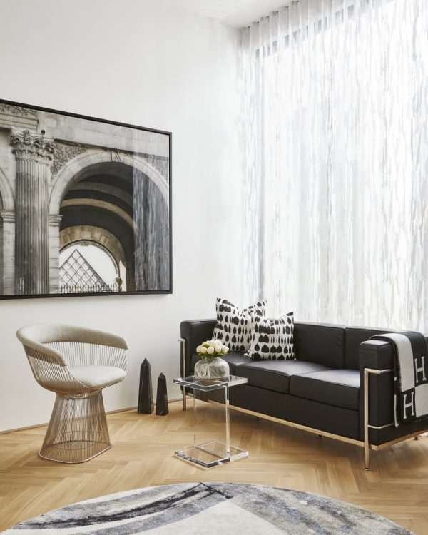 Toronto Interior Design Group, TIDG, TIDG boutique, with black leather couch, white drapes, rug, hardwood floor, acrylic table, architectural art